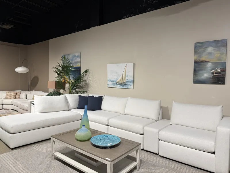 Angled view of the Bassett Beckham sectional (model 2676) with a chaise, coffee table and sailboat artwork in The Sofa Store showroom